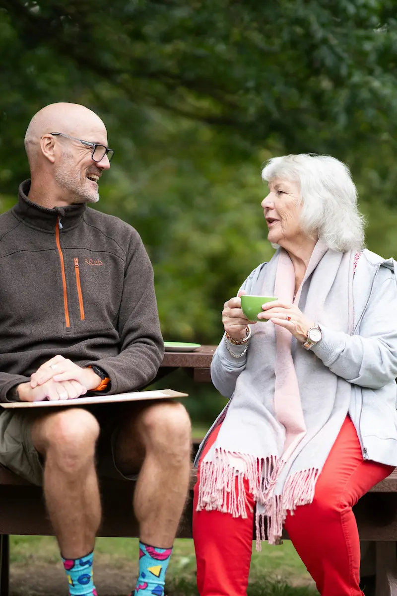 Elderly lady drinking tea in the park with a carer